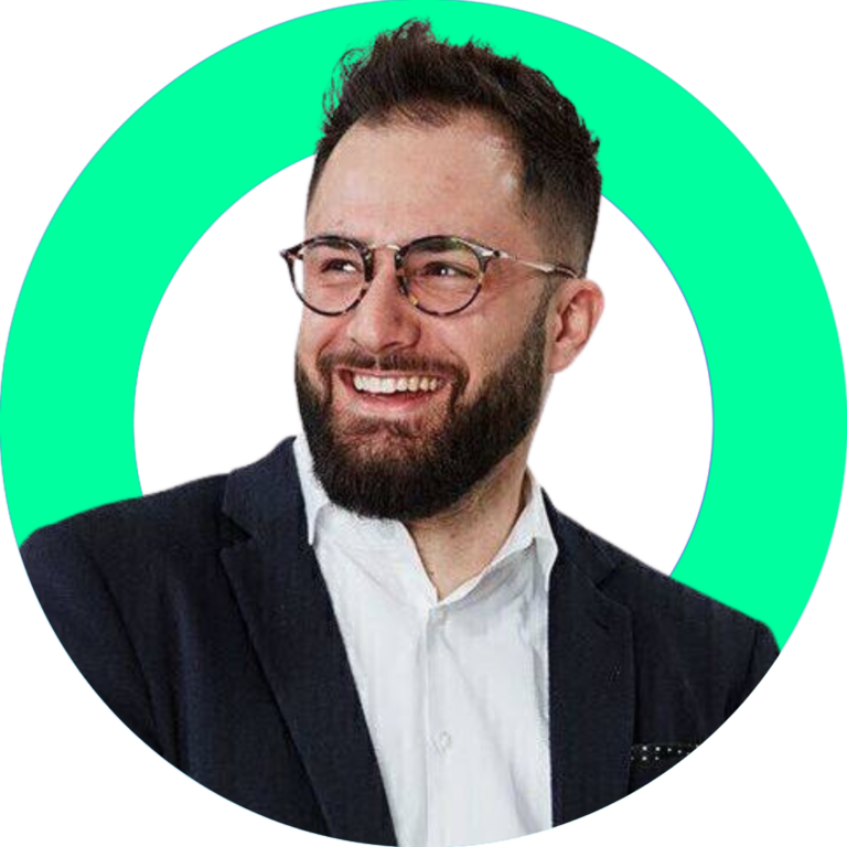 Smiling businessman in tailored suit, stylish glasses, set against green background.