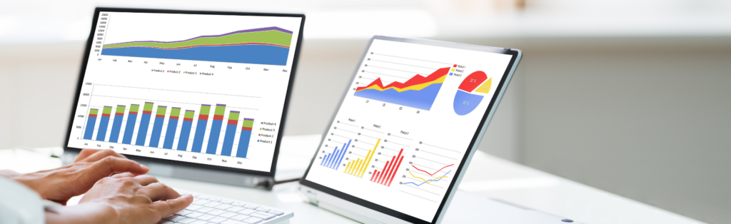 Professional analyzing financial trends on dual screens with colorful graphs in a modern office.