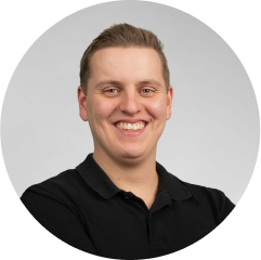 Smiling young man in black polo, professional and friendly profile portrait.