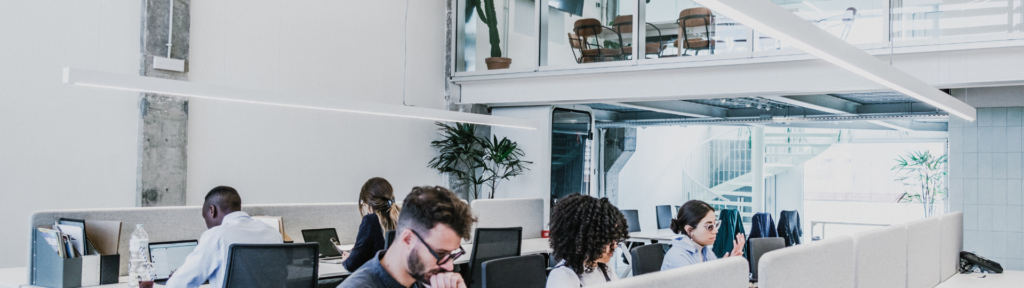 Modernes Großraumbüro mit Mitarbeitern, Teamarbeit und Weiterbildung gemäß Qualifizierungschancengesetz.