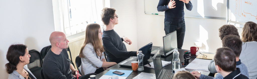 KI-Weiterbildung im Unternehmen: Mitarbeiter lernen gemeinsam in moderner, hell beleuchteter Schulung.